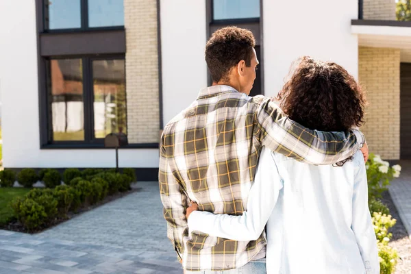 Rückansicht eines afrikanisch-amerikanischen Mannes, der seine Frau umarmt, während er zum Haus geht — Stockfoto