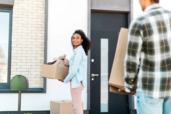 Selective focus of african american woman looking at husband while holding box — Stock Photo