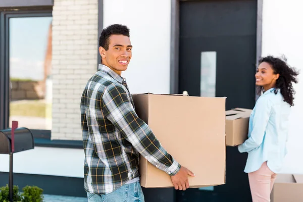 Enfoque selectivo del hombre afroamericano mirando a la cámara mientras sostiene la caja - foto de stock