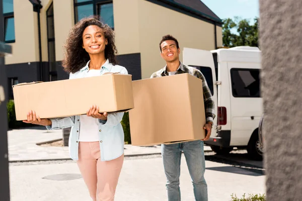 Afrikanisch-amerikanische Frau und Mann halten Kisten und blicken in die Kamera — Stockfoto