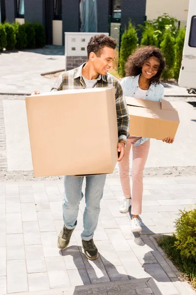 Full length view of african american man looking at woman while holding box — Stock Photo