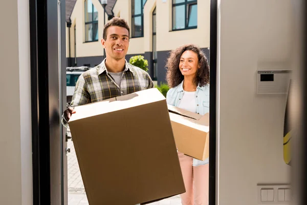 Africano americano hombre caminando en casa mientras holding caja - foto de stock