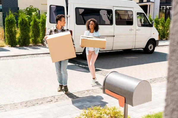 Full length view of african american man and woman holding boxes and looking at each other — Stock Photo
