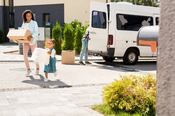 Full length view of african american mother and daughter running to house with some stuff — Stock Photo