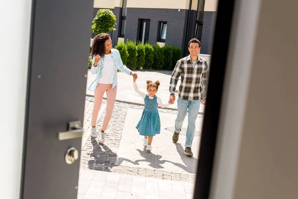 Vista completa dei genitori afro-americani che si tengono per mano con il bambino mentre entrano in casa — Foto stock