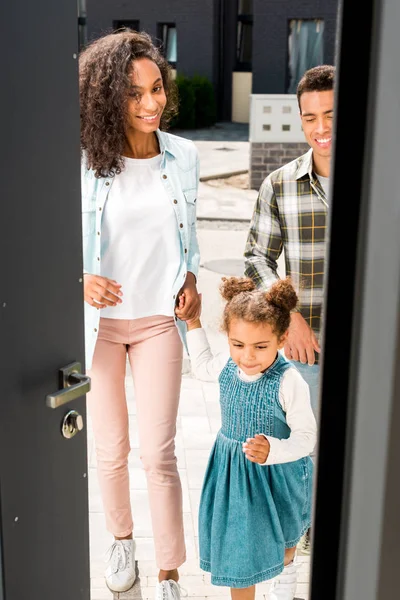 Vue pleine longueur du couple afro-américain avec enfant entrant dans la maison — Photo de stock