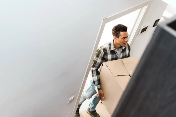 High angle view of handsome african american man holding box and looking away — Stock Photo