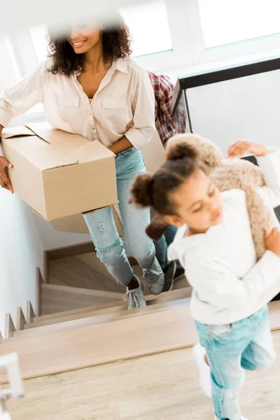 Selective focus of african american mother going upstairs while kid holding teddy bear — Stock Photo