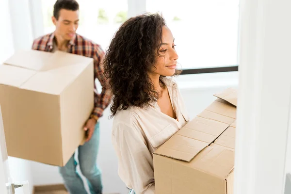 Selective focus of african american woman holding box while man going upstairs — Stock Photo