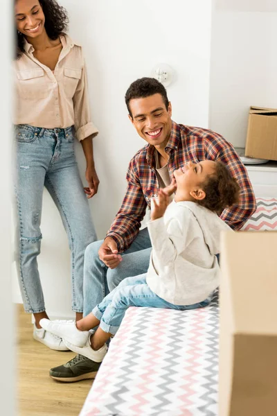 Full length view of african american couple with cute kid smiling while sitting on bed — Stock Photo