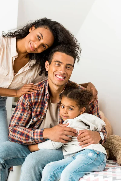 Africano americano donna abbracciare marito mentre padre abbracciare figlia e guardando fotocamera — Foto stock