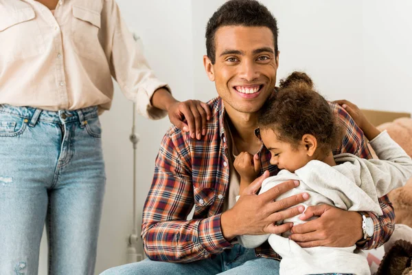 Abgeschnittene Ansicht einer Frau, die neben einem afrikanisch-amerikanischen Mann steht, während der Vater Kind umarmt — Stockfoto