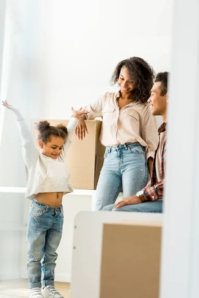 Vista completa de niño afroamericano de pie cerca de la madre y el padre - foto de stock