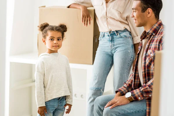 Cropped view of african american mother leaning on and father looking at child while kid looking at camera — Stock Photo