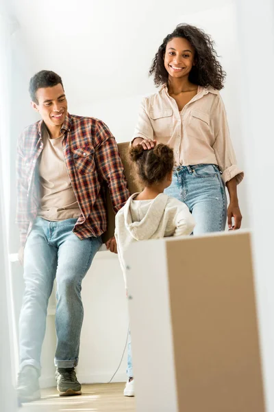 Selective focus of african american woman looking at camera and touching head of daughter while father looking at kid — Stock Photo