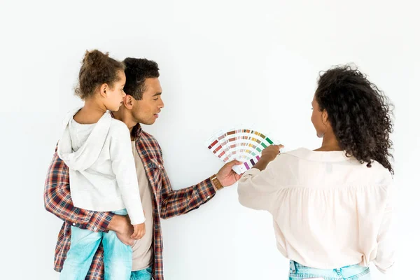 Afro-américain père et mère essayant de choisir la couleur pour leur mur de palette colorée tandis que l'homme tenant enfant isolé sur blanc — Photo de stock