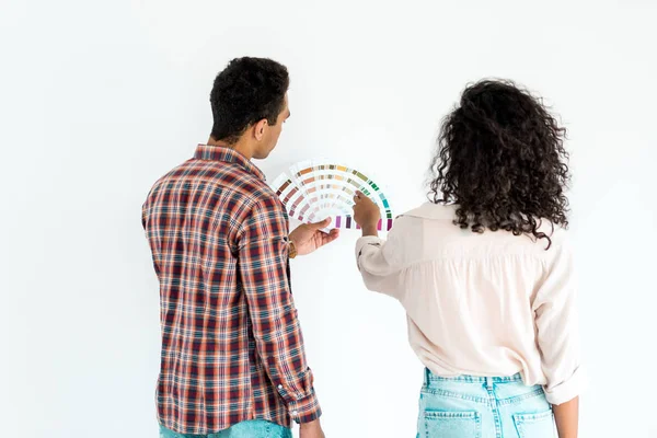 African american woman and man trying to choose color for their wall from colorful palette isolated on white — Stock Photo