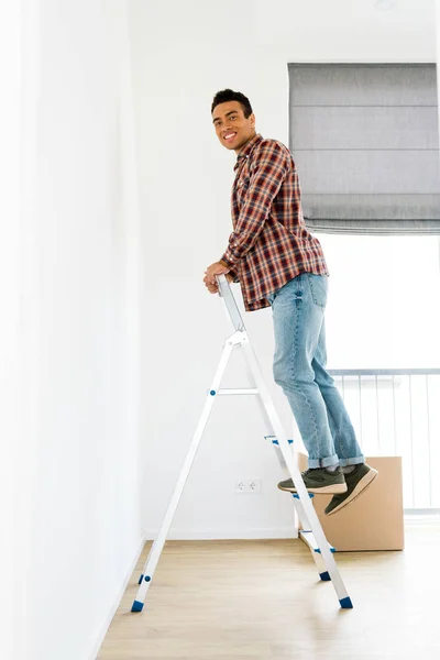 Vista completa de hombre afroamericano de pie en la escalera y mirando a la cámara - foto de stock