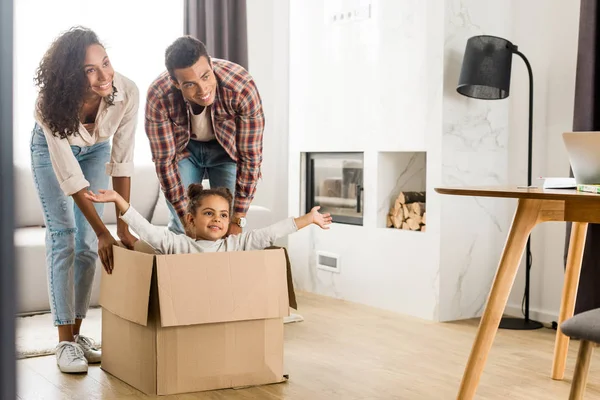 Full length view of african american parents playing with kid while child sitting in box — Stock Photo