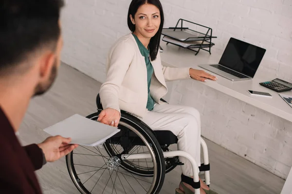 Vista recortada del gerente dando documentos a la mujer de negocios discapacitada en el cargo - foto de stock