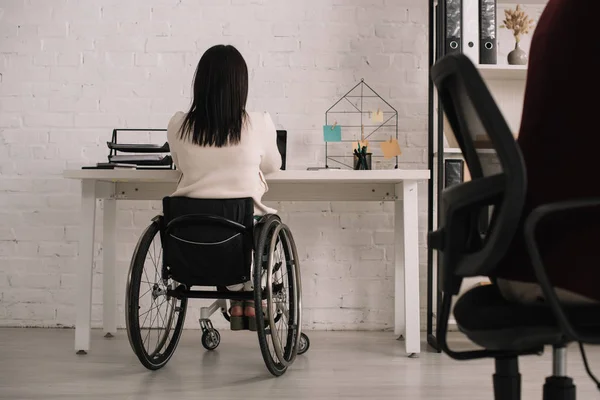 Вид ззаду бізнес-леді, що сидить на робочому місці в інвалідному візку — стокове фото