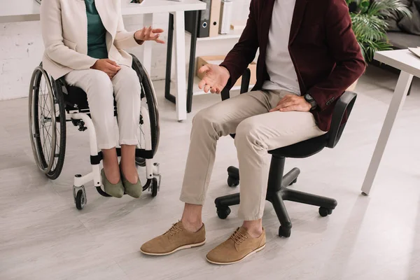 Cropped view of disabled businesswoman in wheelchair near business partner in office — Stock Photo