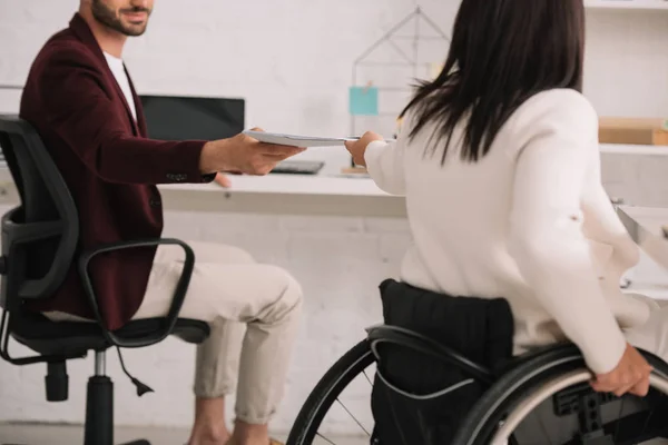 Cropped view of disabled businesswoman giving documents to colleague in office — Stock Photo