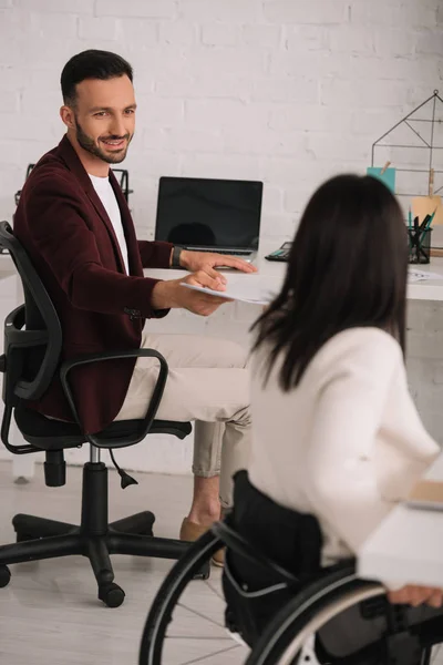 Handsome businessman giving documents to disabled businesswoman in office — Stock Photo