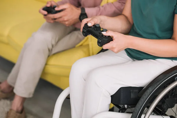 KYIV, UCRANIA - 10 de julio de 2019: Vista parcial de una mujer discapacitada jugando videojuegos con su novio en casa . - foto de stock