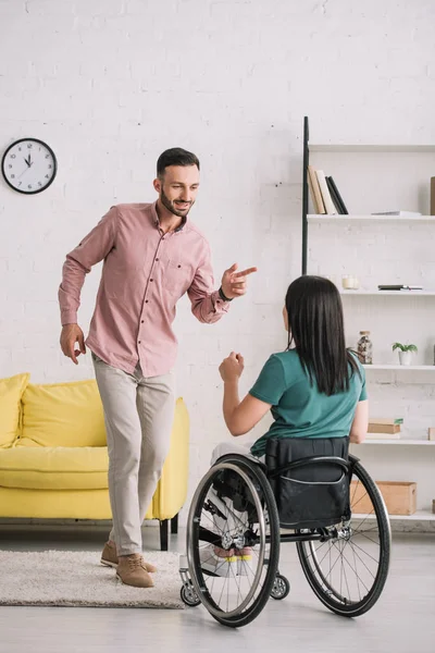 Vue arrière de jeune femme handicapée en fauteuil roulant dansant avec petit ami gai à la maison — Photo de stock