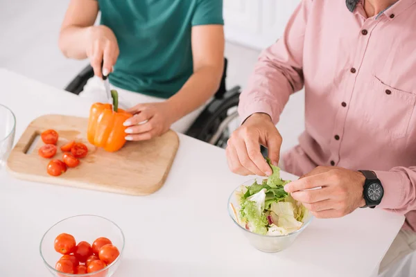 Cropped view of disabled woman with boyfriend preaparing salad together — Stock Photo
