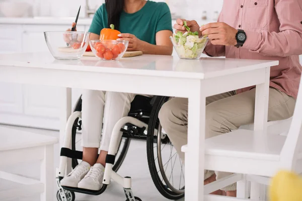 Vista parziale della donna disabile in sedia a rotelle che cucina insieme al fidanzato in cucina — Foto stock