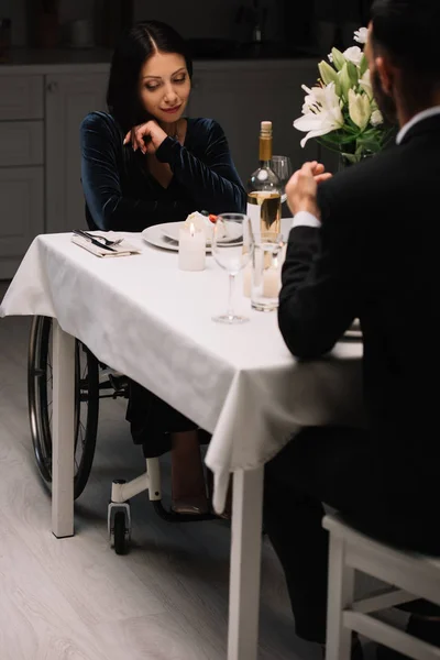 Vista trasera del hombre teniendo una cena romántica con hermosa novia discapacitada - foto de stock