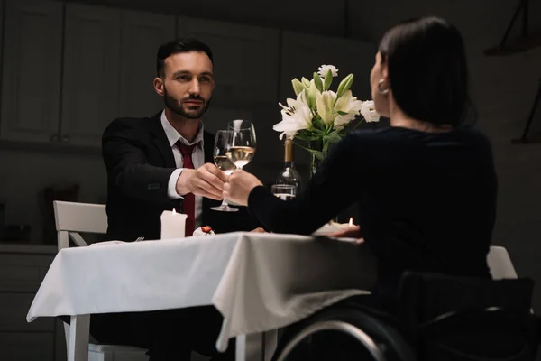 Vue arrière de la jeune femme handicapée cliquetis verres de vin rouge avec beau petit ami pendant le dîner romantique — Photo de stock