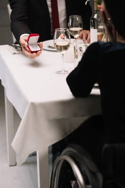 Visão parcial do namorado fazendo proposta de casamento para mulher jovem deficiente enquanto tendo jantar romântico — Fotografia de Stock