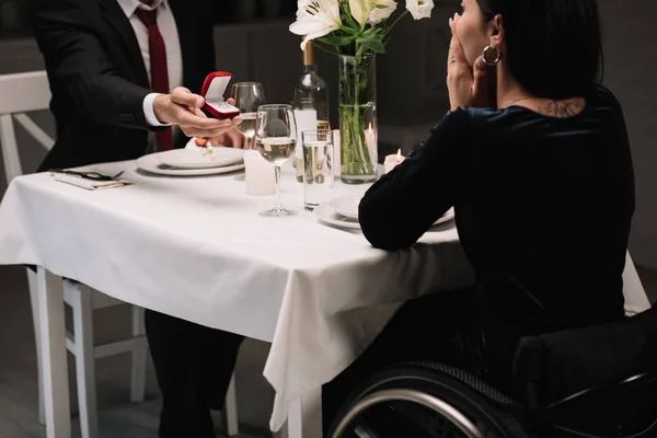 Vue recadrée de jeune homme faisant la demande en mariage à petite amie handicapée tout en ayant dîner romantique — Photo de stock