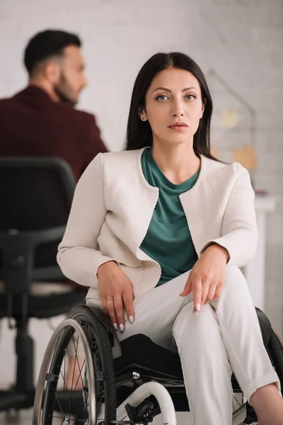 Confident disabled businesswoman looking at camera while sitting in wheelchair in office — Stock Photo