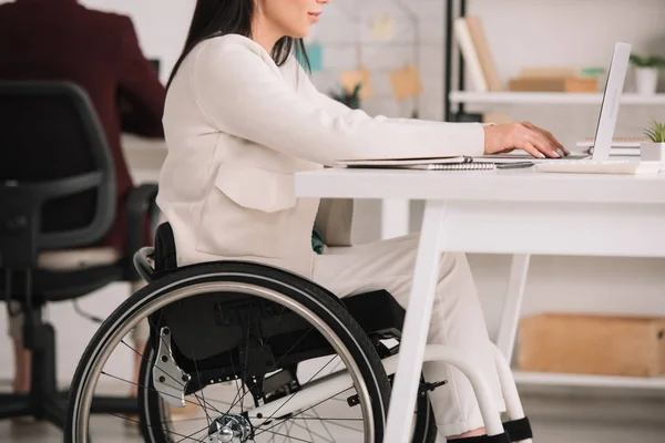 Vue recadrée d'une femme d'affaires handicapée assise en fauteuil roulant sur le lieu de travail — Photo de stock