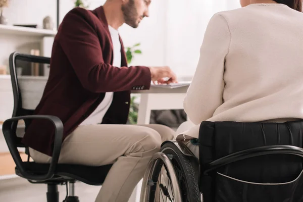 Vista recortada de la mujer de negocios discapacitada sentada en el escritorio cerca de colega - foto de stock