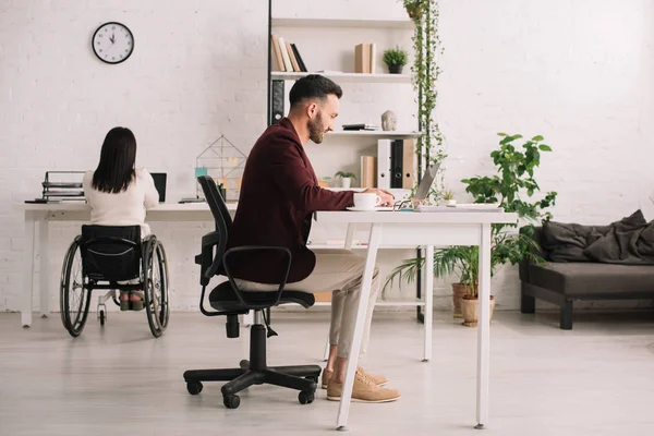 Hombre de negocios guapo y mujer de negocios discapacitada que trabaja en el cargo - foto de stock