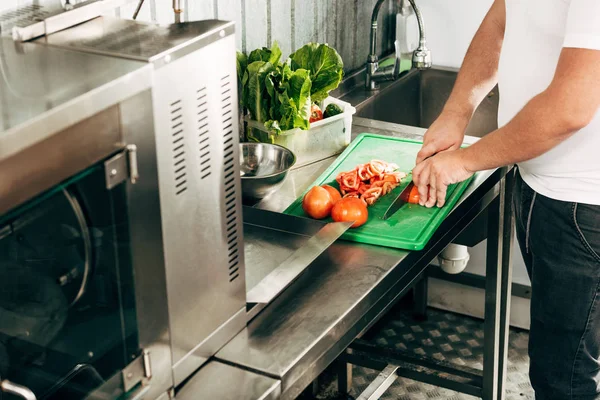Partial view of cook cutting tomatoes on chopping board — Stock Photo