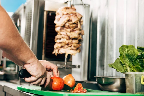 Partial view of cook cutting tomatoes on chopping board — Stock Photo