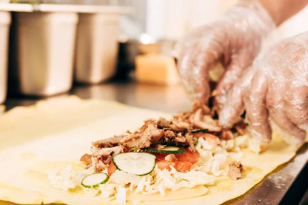 Vista parcial de cocinero en guantes preparando doner kebab - foto de stock