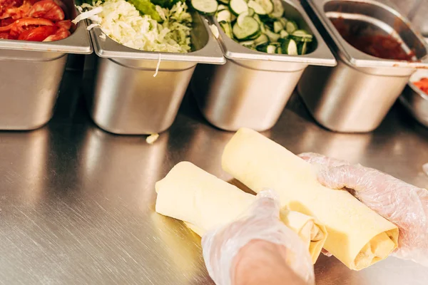 Partial view of cook in gloves holding doner kebabs at table — Stock Photo