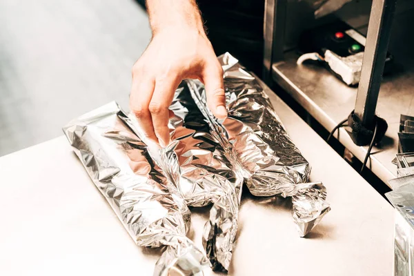 Vista cortada do homem e doner kebabs em folha de alumínio — Fotografia de Stock