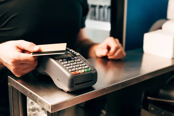 Ausgeschnittene Ansicht eines Mannes mit Kreditkarte am Zahlungsterminal — Stockfoto
