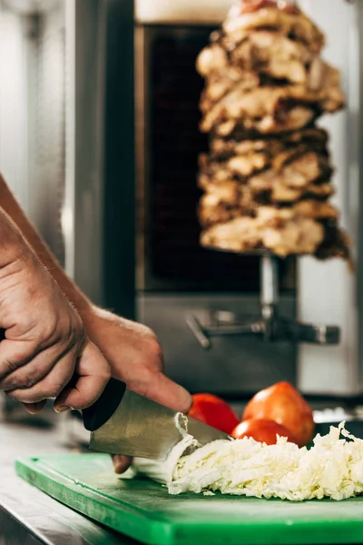 Partial view of cook cutting lettuce on cutting board — Stock Photo