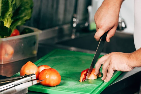 Abgeschnittene Ansicht von Koch, der Tomaten auf Schneidebrett schneidet — Stockfoto