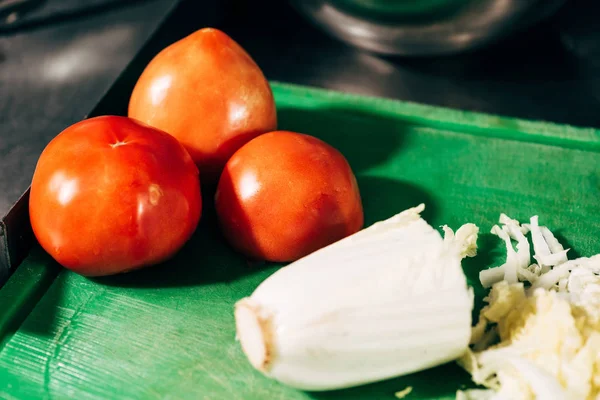 Foco seletivo de tomates e alface cortada em tábua de corte verde — Fotografia de Stock