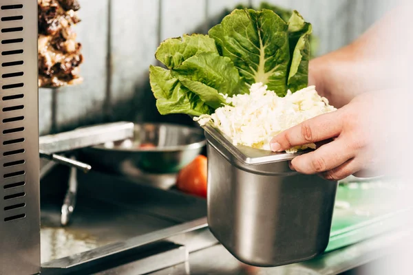 Cropped view of cook holding container with cut lettuce — Stock Photo